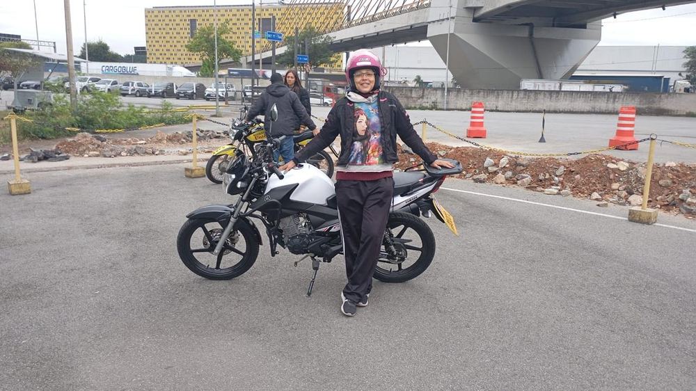 Aluna com capacete ao lado da moto durante o treino de habilitação categoria A na Mooca