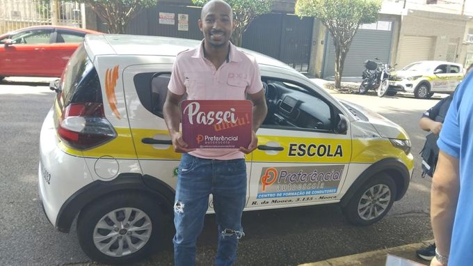Aluno aprovado segurando a placa Passei ao lado do carro da Preferencial Autoescola na Mooca